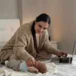 mãe com bebê ao lado fazendo sessão de terapia online pelo notebook em casa
